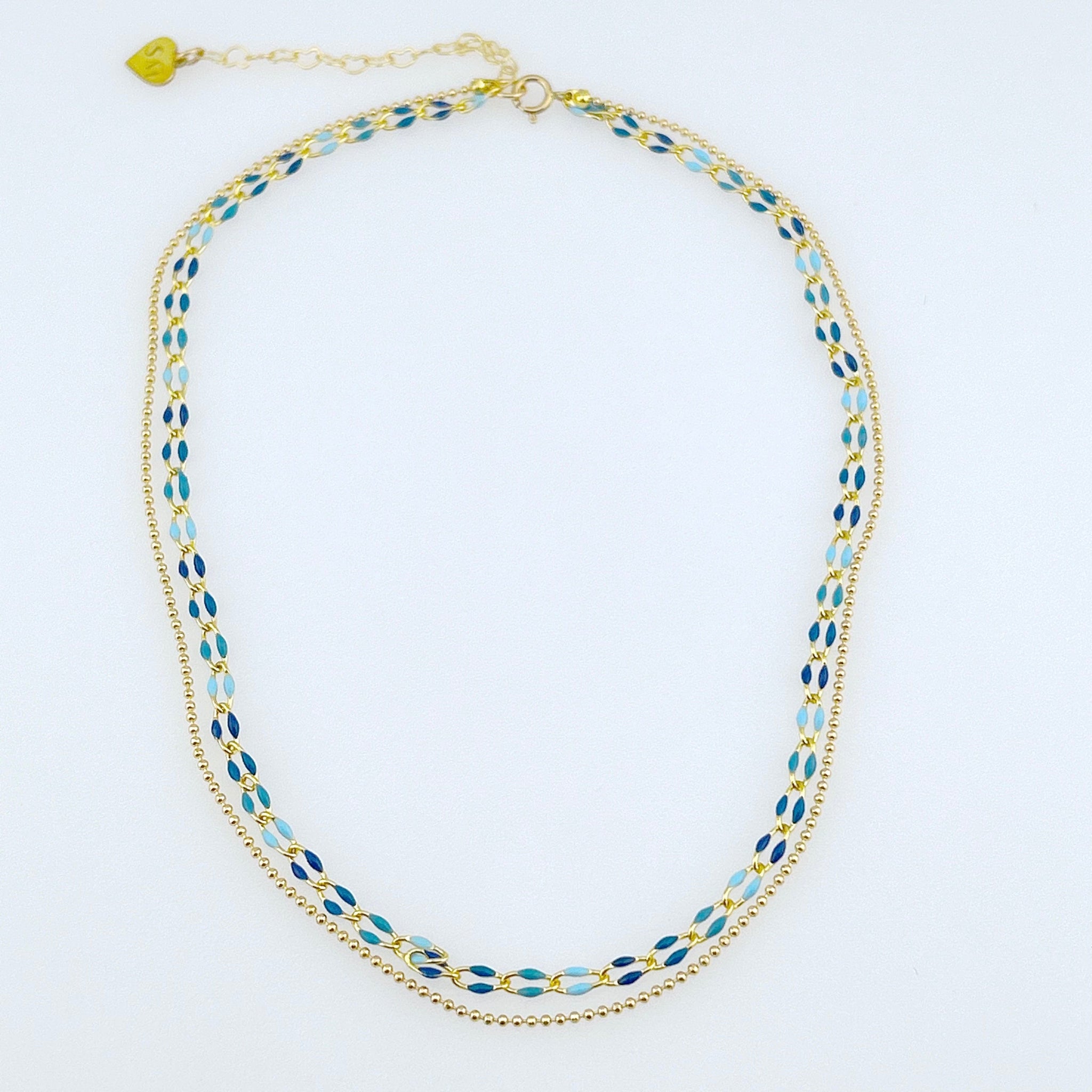 Picture of a two layer style chain, one layer is a open link style with enamel colors of light blue, medium blue and dark blue. the second chain is a tiny beaded style chain.