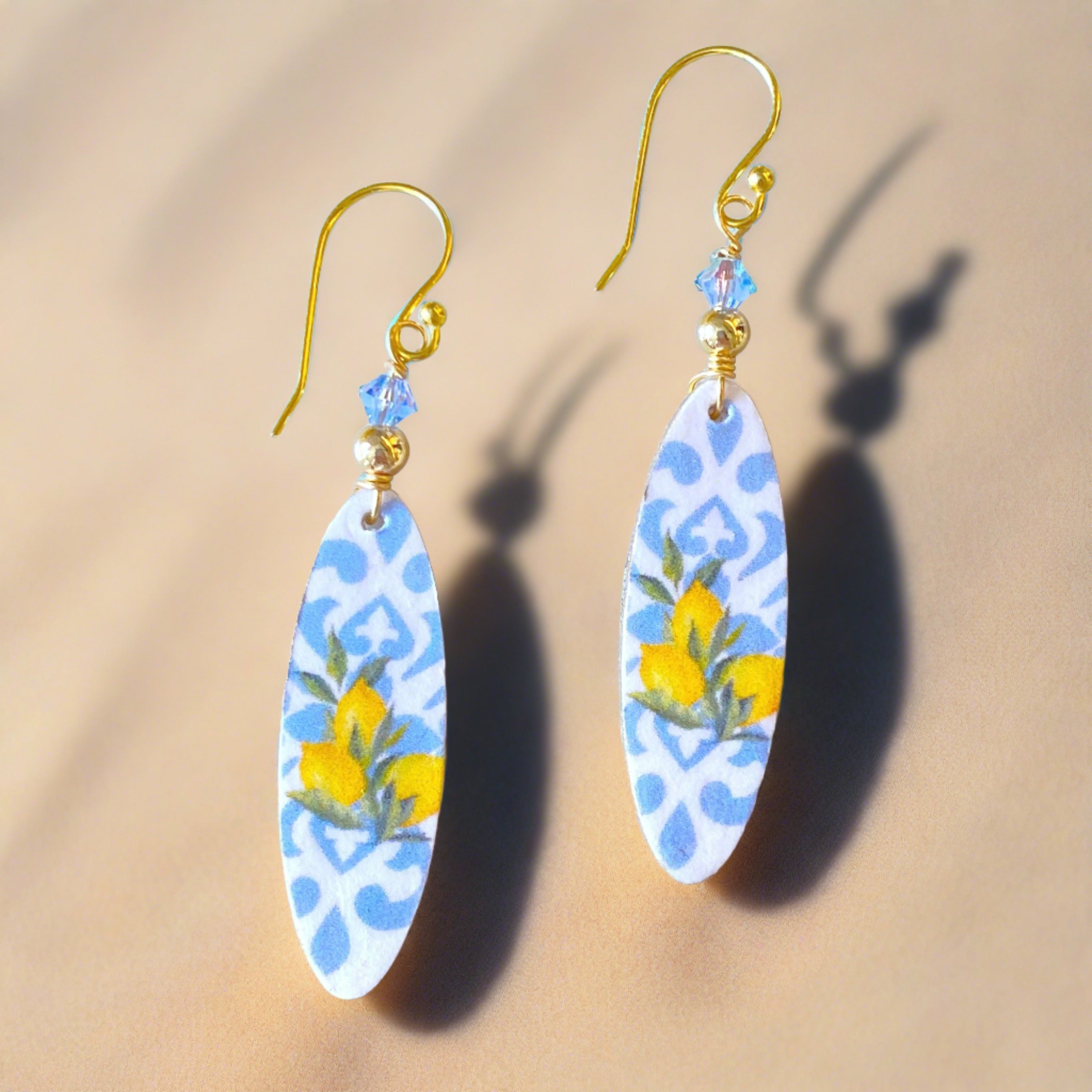 surboard shaped earrings that have an italian tile print and lemons on the front, adorned with a blue crystsal at the top and on fishhook style ear hooks