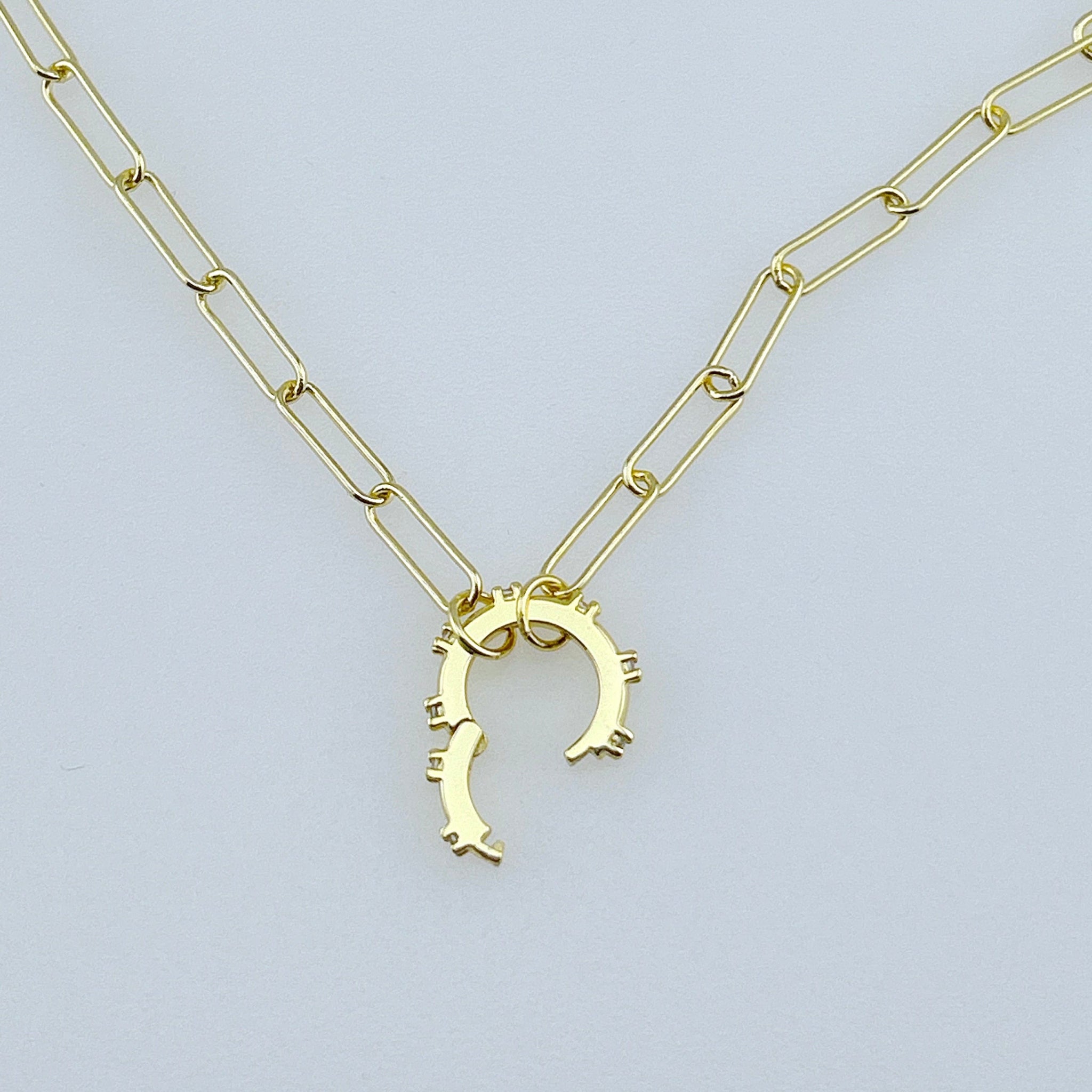Picture of a gold paper clip chain with a circular center connector that is open to show how you can open it to add a charm
