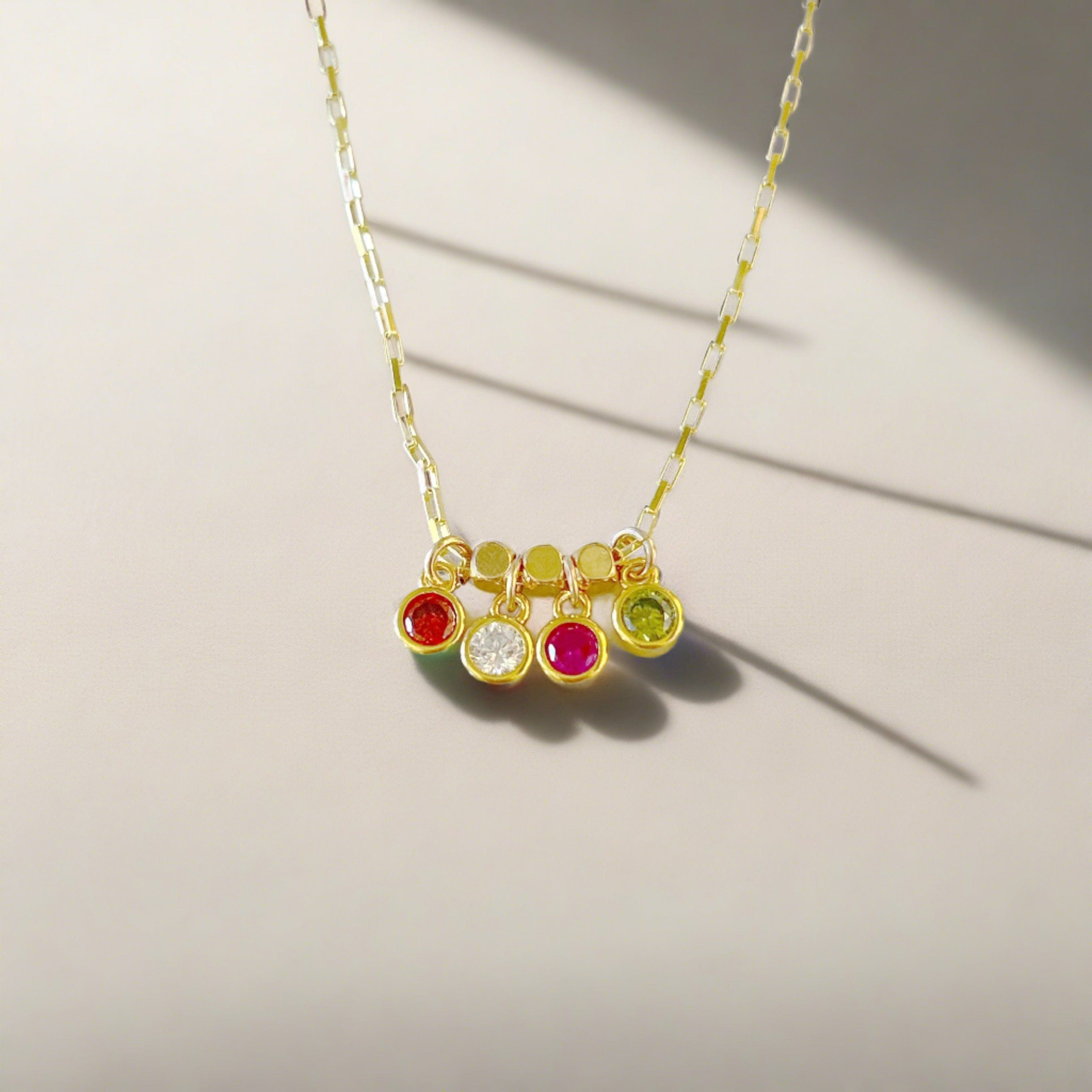 Gold paperclip style necklace featuring 4 different birthstones separated by cube shape beads , a gift for a mom for mothers day or her birthday. Features a garnet , diamond, ruby, and peridot