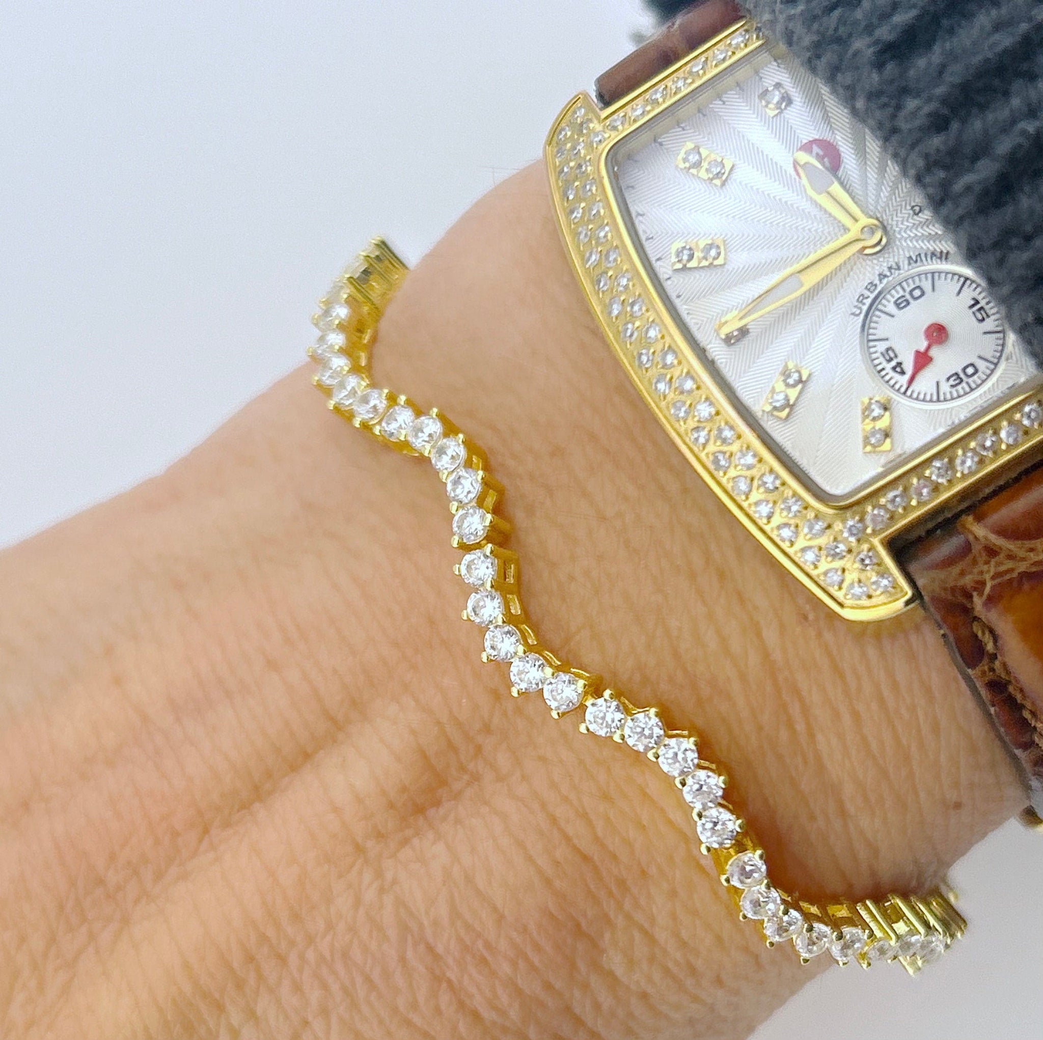 picture of a wrist with the wavy style tennis bracelet on and a watch 